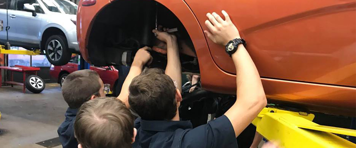 Students looking in wheel well of car